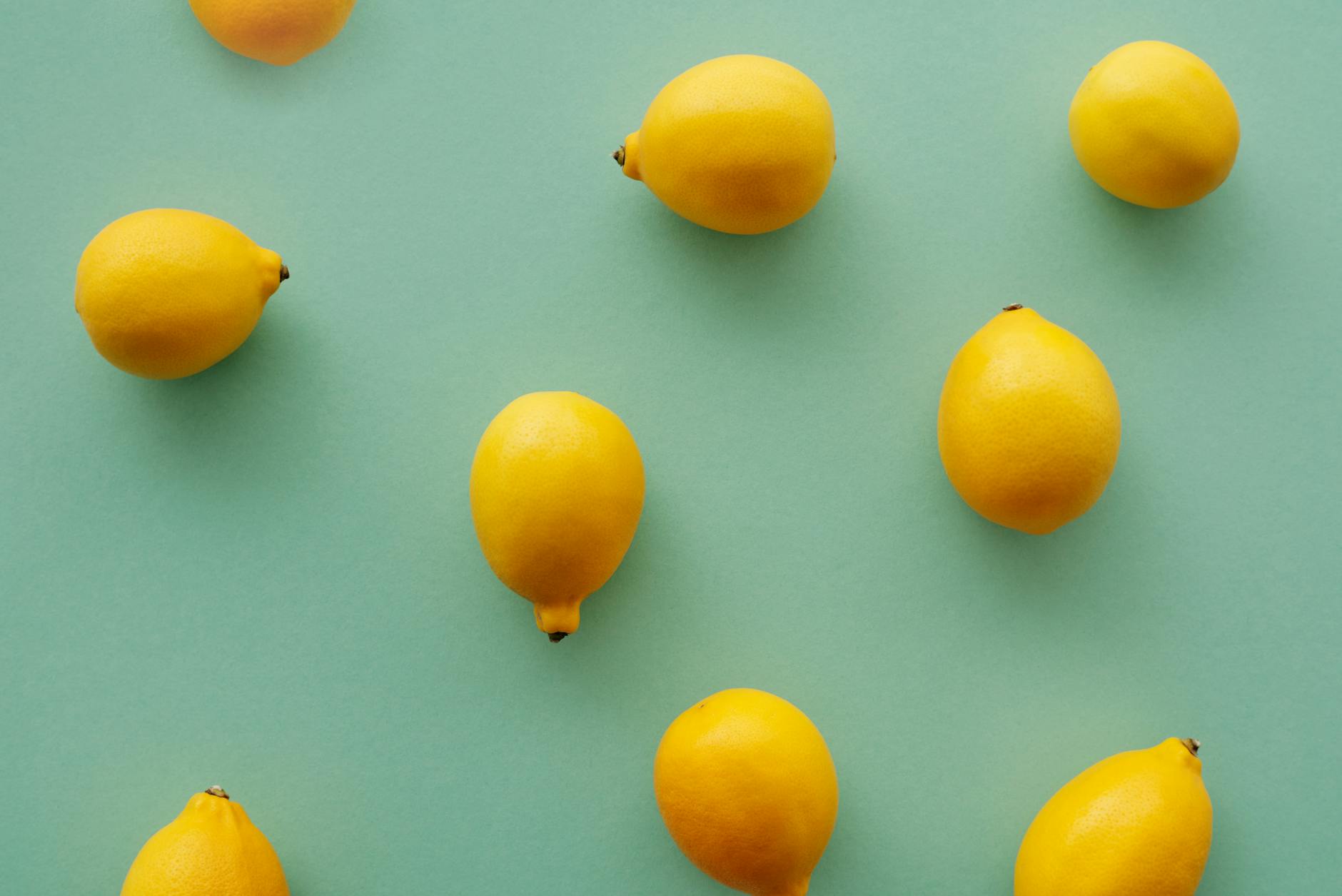 Bright yellow lemons arranged on a pastel green background, symbolizing the fresh sensation of Hello Nancy lemon clitoral vibrators.