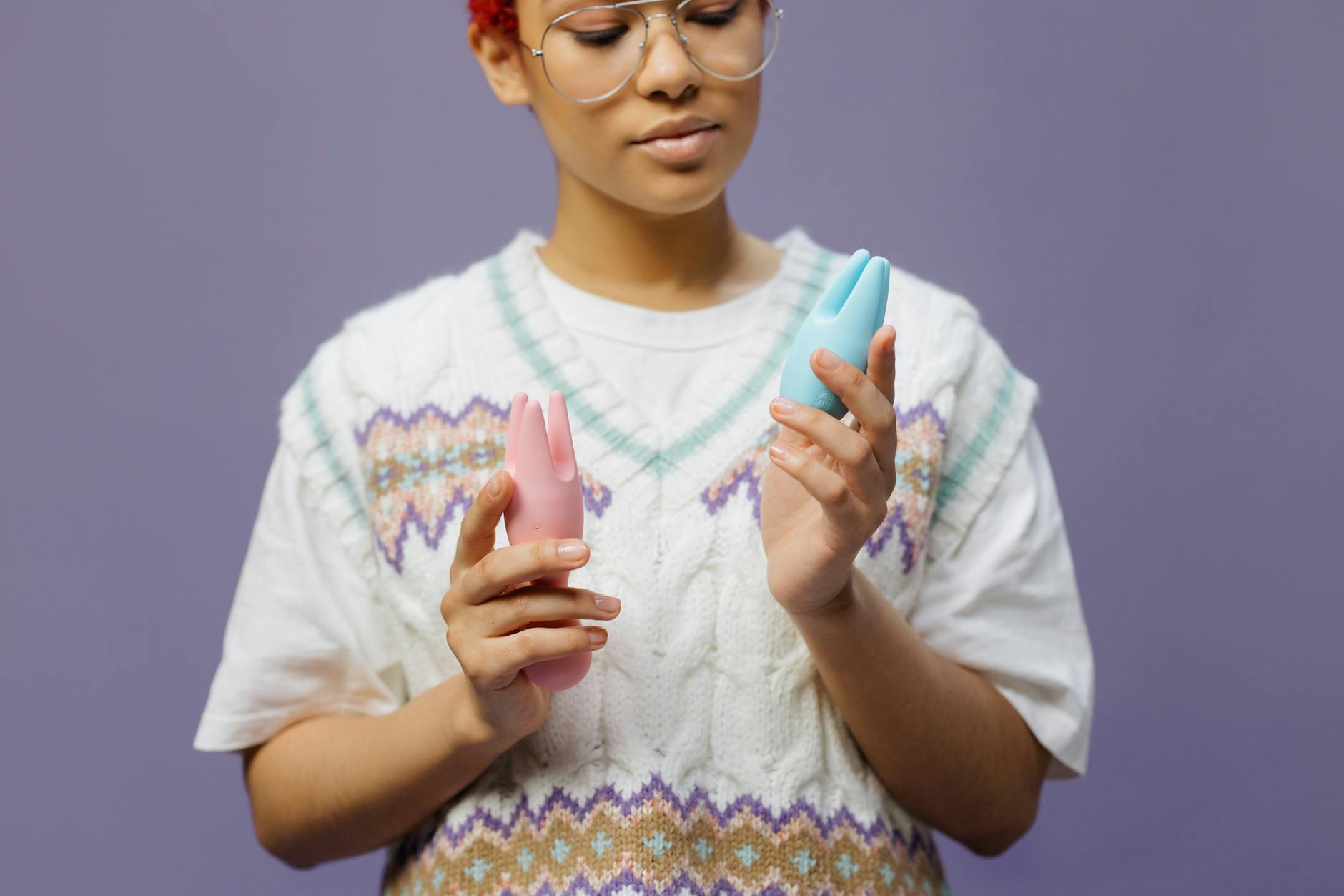 Woman holding colorful vibrators, contemplating how to ask for pleasure